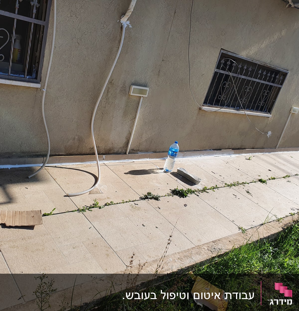 בקבוק מים וכלי עבודה על שביל מרוצף ליד קיר